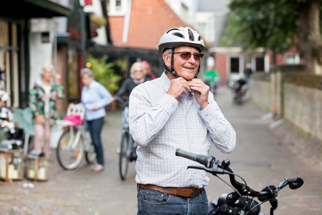 Oudere man maakt zijn fietshelm vast