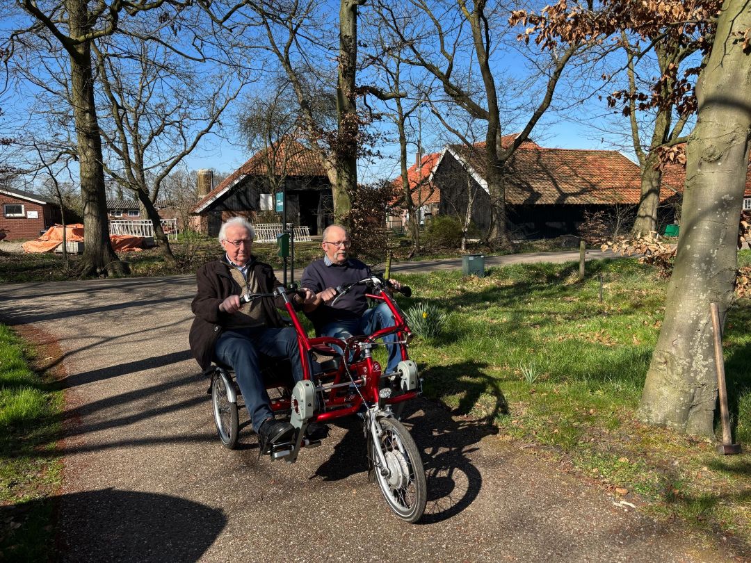 Twee oudere mannen op een elektrische duofiets
